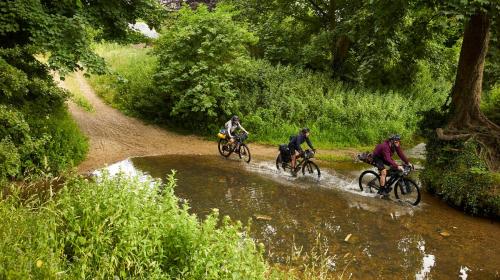 Cyclists riding through a ford in the countryside